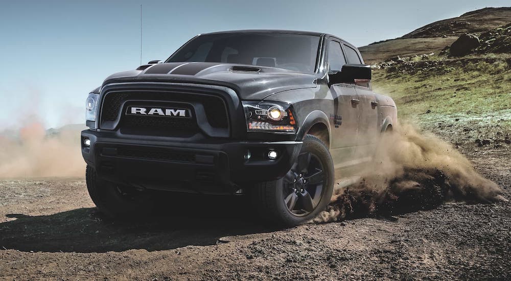 A popular used Ram truck in Lexington, a black 2020 Ram 1500 Classic Warlock, is kicking up dirt on a trail.