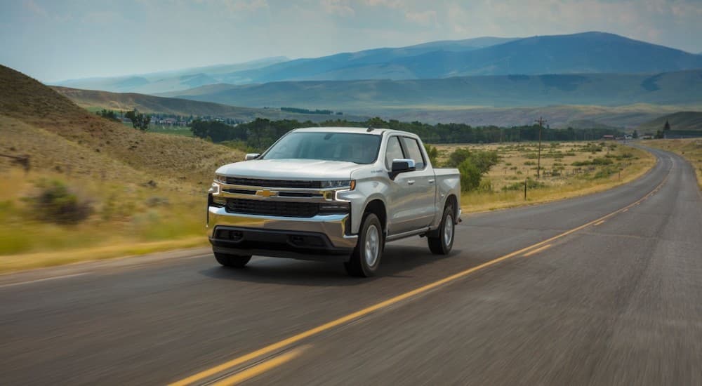 A silver 2020 Chevy Silverado LT is driving on a highway after leaving a used truck dealer.