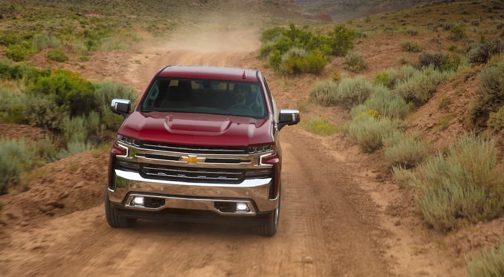 A red 2020 Chevy Silverado 1500 is shown from the front driving on a dirt road.