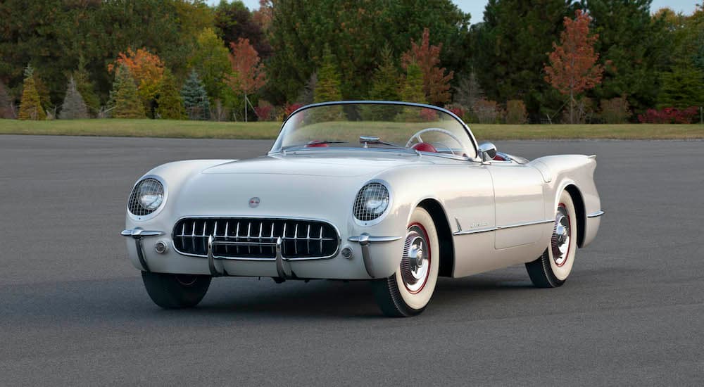A white 1954 Chevy Corvette is shown parked in an empty parking lot.
