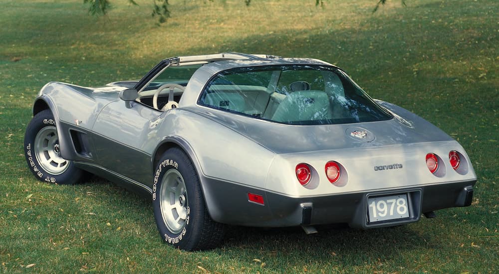 A silver 1978 Chevy Corvette is shown from the rear parked in a field.