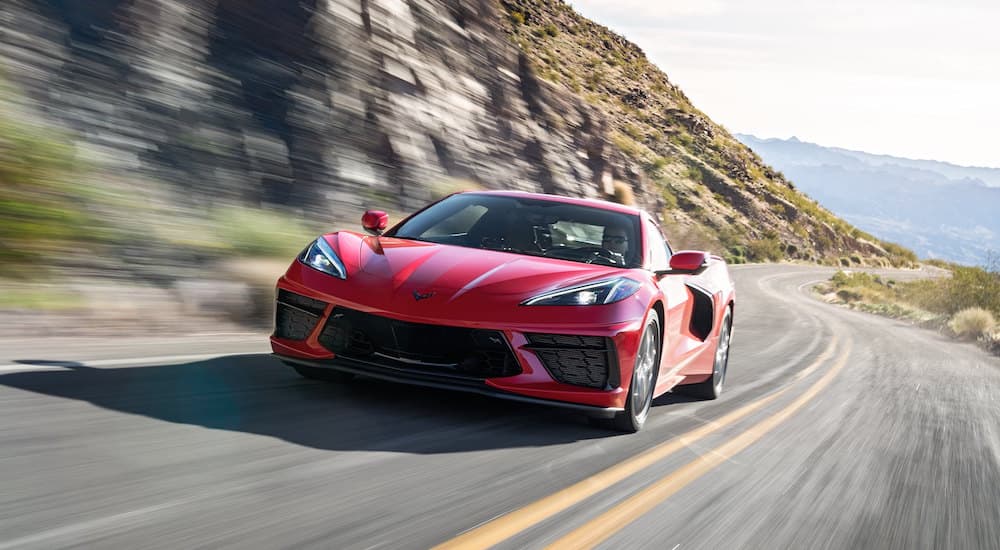 A red 2021 Chevy Corvette is shown from the front driving past a cliff face.