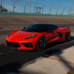 An orange 2021 Chevy Corvette is parked on the tarmac at a racetrack.