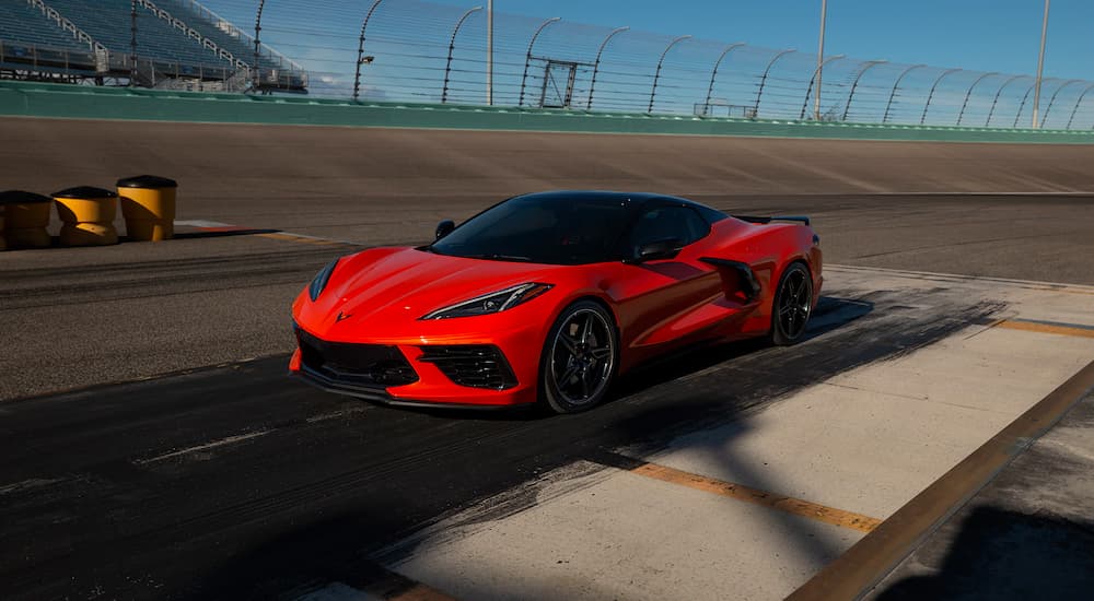 An orange 2021 Chevy Corvette is parked on the tarmac at a racetrack.