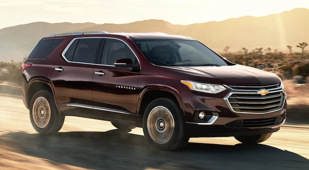 A maroon 2021 Chevy Traverse is speeding down a dusty road.