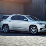 A silver 2021 Chevy Traverse is shown from the side parked on a paver driveway.