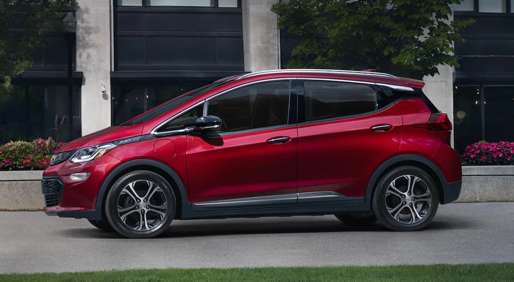 A red 2021 Chevy Bolt EV is parked in front of a black and grey building.