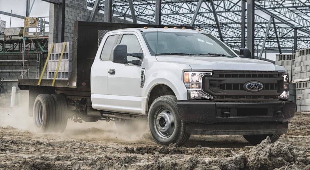A white 2021 Ford Chassis Cab F-350 Flatbed is carring cinder blocks on a construction site.