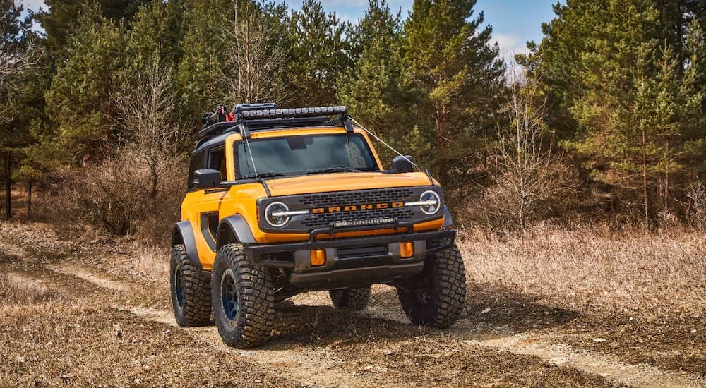 A yellow 2021 Ford Bronco 2-door is driving on a dirt trail.