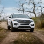 A white 2021 Ford Explorer is shown from the front driving on a dirt trail as part of the 2021 Ford Explorer vs 2021 Ford Bronco comparison.