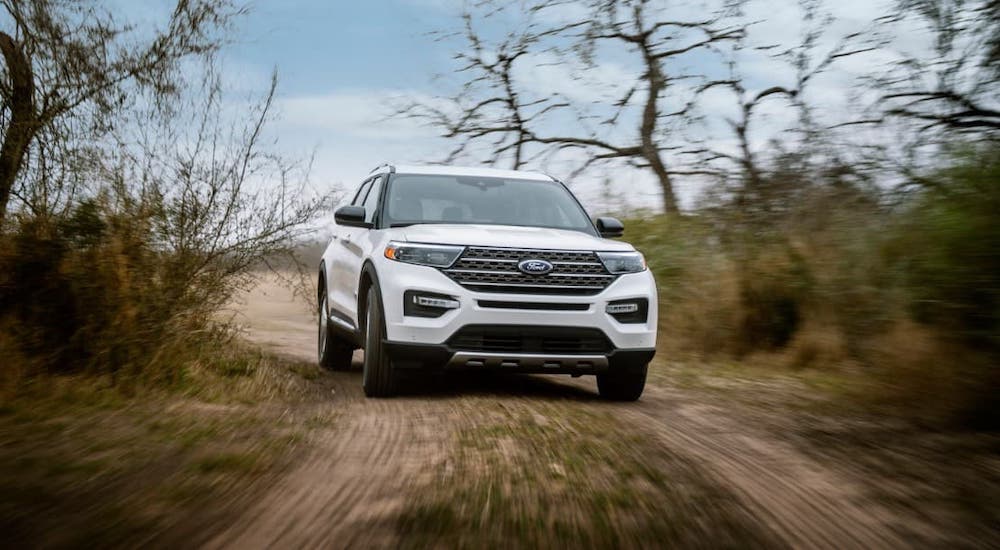 A white 2021 Ford Explorer is shown from the front driving on a dirt trail as part of the 2021 Ford Explorer vs 2021 Ford Bronco comparison.