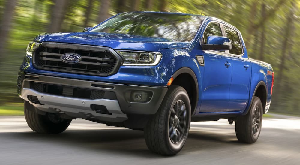 A blue 2021 Ford Ranger is driving on a tree-lined road.