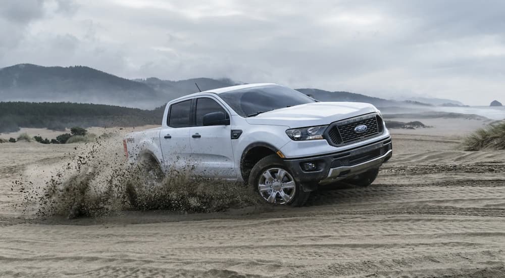 A white 2021 Ford Ranger is off-roading in sand.