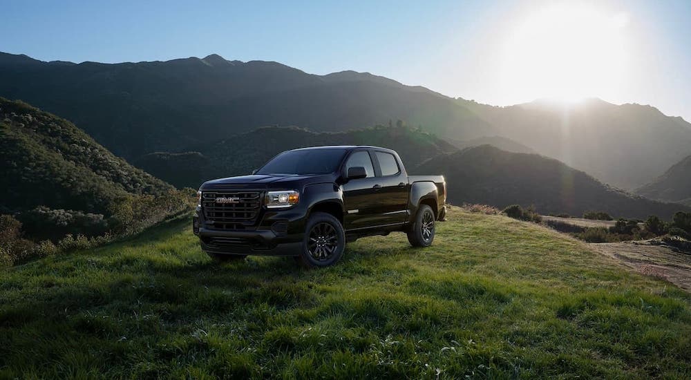 A black 2021 GMC Canyon crew cab is parked on a grassy mountain.