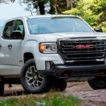 A white 2021 GMC Canyon AT4 is parked on a woodland trail.