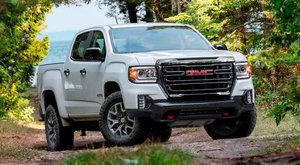 A white 2021 GMC Canyon AT4 is parked on a woodland trail.