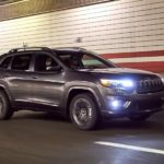 A gray 2021 Jeep Cherokee is driving in a tunnel with the lights on.