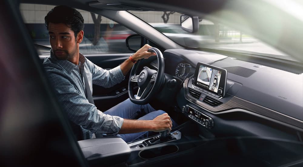 A man is shown from the passenger side of a 2021 Nissan Altima while backing up.