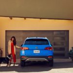 A woman is shown opening the door of a blue 2022 Volkswagen Taos.
