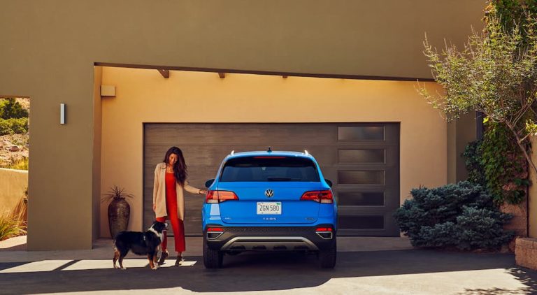 A woman is shown opening the door of a blue 2022 Volkswagen Taos.