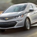 A silver 2021 Chevy Bolt EV is driving on a blurry rural road.