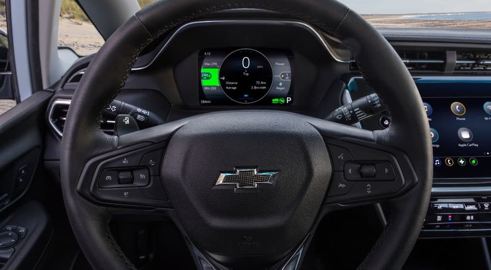 A closeup shows the black steering wheel and information cluster on a 2022 Chevy Bolt EV.