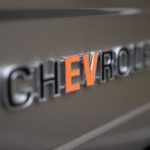 A closeup shows the badging on a gold SEMA 360 Blazer concept where the 'EV' in Chevrolet is orange.