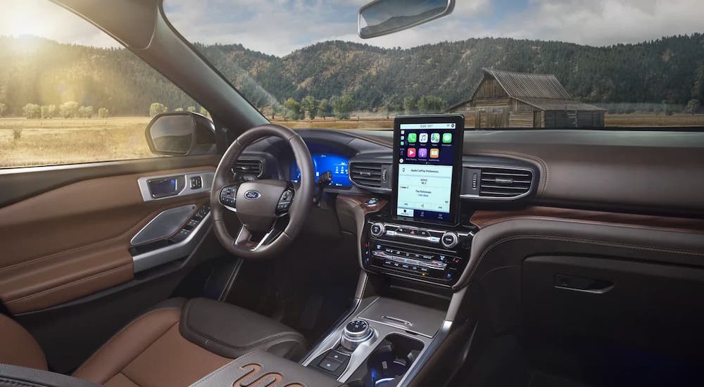 The black and brown interior is shown, overlooking a cabin and mountains, in a 2021 Ford Explorer.