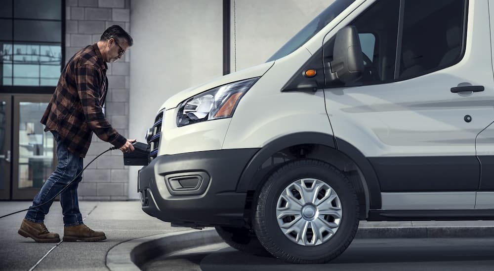A white 2022 Ford E-Transit is shown from the side while being charged.