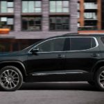 A black 2021 GMC Acadia Denali is shown from the side driving through the city after leaving a GMC dealer near you.