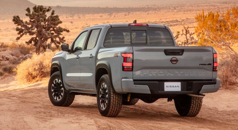A gray 2022 Nissan Frontier is shown from the rear, parked on a dirt road.