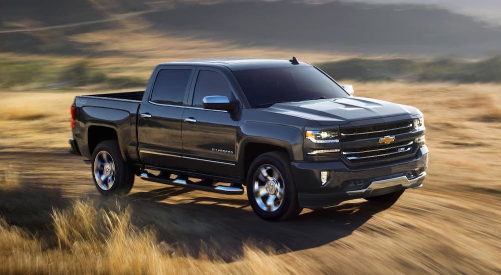 A black 2018 Chevy Silverado 1500, a popular used truck for sale, is driving on a dirt road.