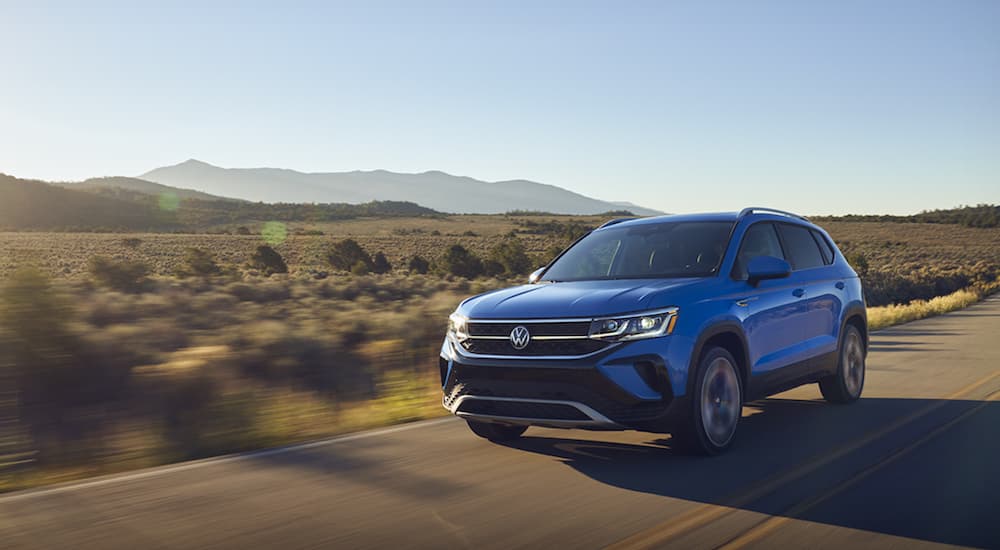 A blue 2022 Volkswagen Taos is driving down a deserted desert road.