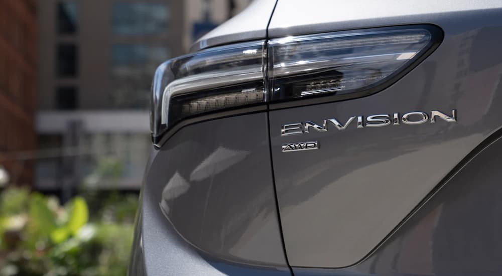 The rear tail light of a 2021 Buick Envision is shown in a city.