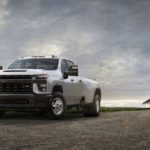 A white 2021 Chevy Silverado 3500HD is parked in front of a white barn.