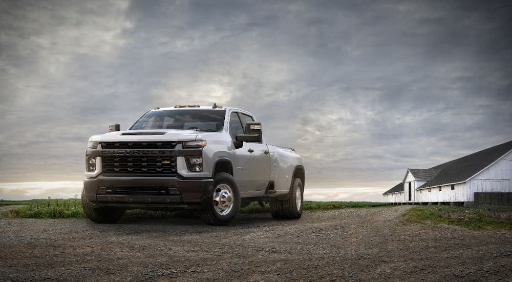 A white 2021 Chevy Silverado 3500HD is parked in front of a white barn.