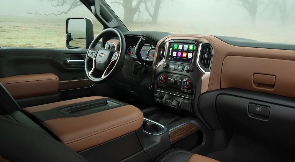 The brown and black interior of a 2021 Chevy Silverado 3500HD is shown from the passenger's side.
