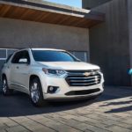 A family is walking towards a white 2021 Chevy Traverse that is parked in a driveway.