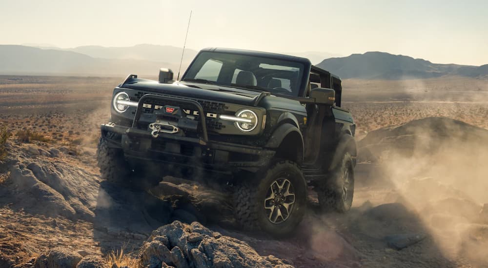 A black 2021 Ford Bronco is off-roading in the desert after winning the 2021 Ford Bronco vs 2021 Jeep Wrangler comparison.