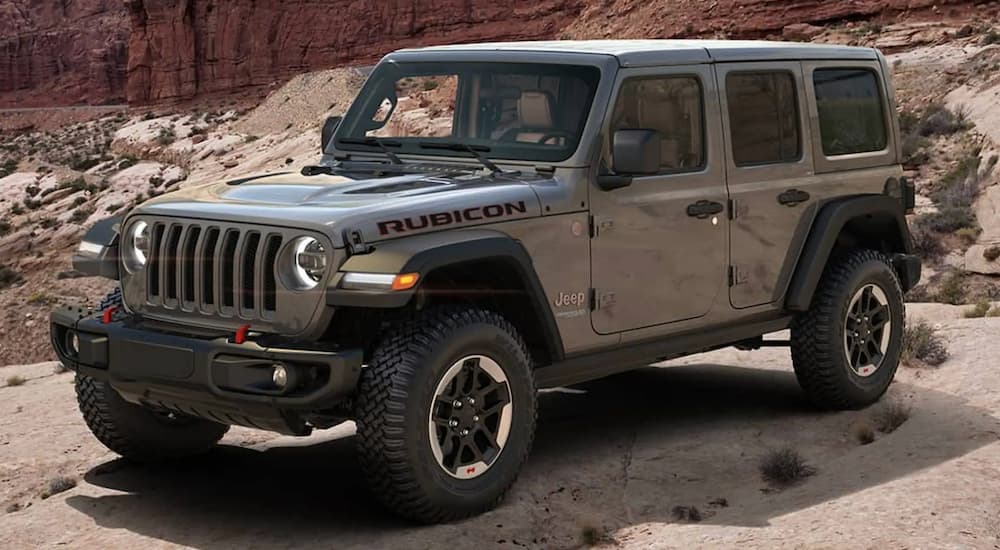 A grey 2021 Jeep Wrangler Rubicon Unlimited is parked in front of desert rocks.