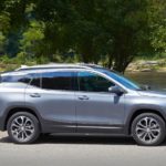 A silver 2021 GMC Terrain is shown from the side driving in front of a river.