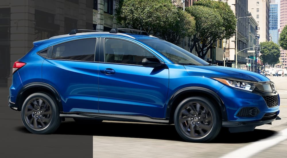 A blue 2021 Honda HR-V Sport is shown from the side driving through the city.