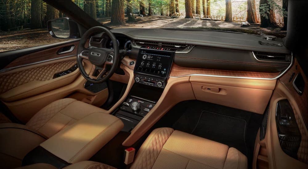 The tan and black interior and dashboard of a 2021 Jeep Grand Cherokee L are shown.