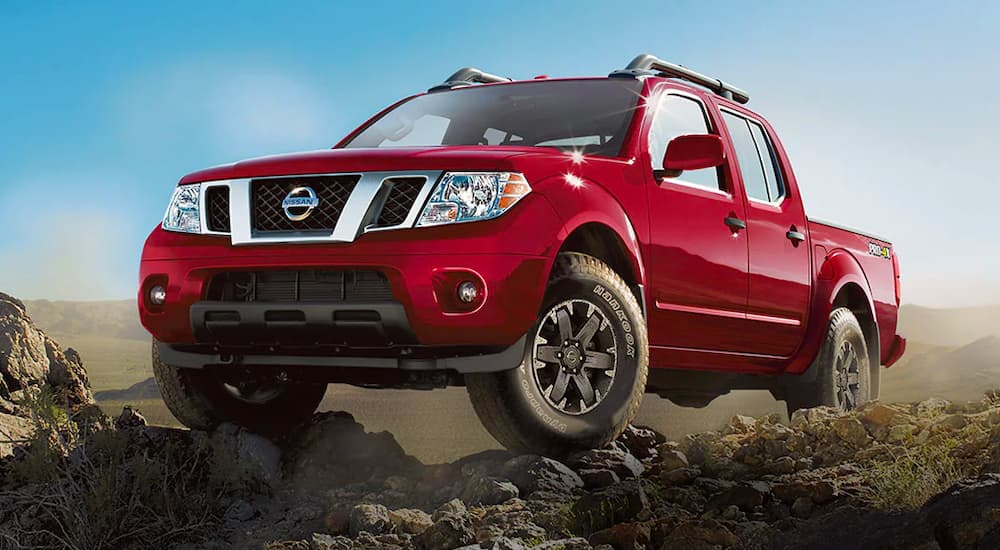 A red 2021 Nissan Frontier PRO-4X is shown from the front parked on a rock formation.