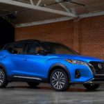 A blue 2021 Nissan Kicks is shown from the side parked in front of a red brick wall.