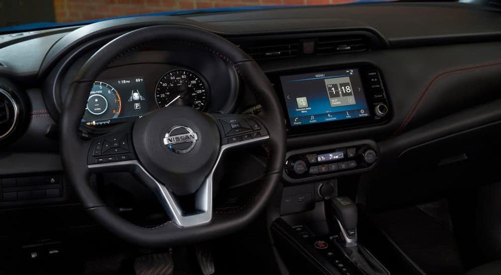 The steering wheel, dashboard and black interior of a 2021 Nissan Kicks are shown.