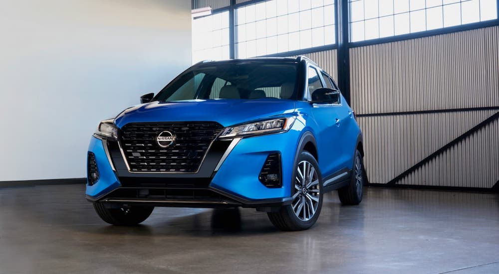 A blue 2021 Nissan Kicks is parked in a warehouse.