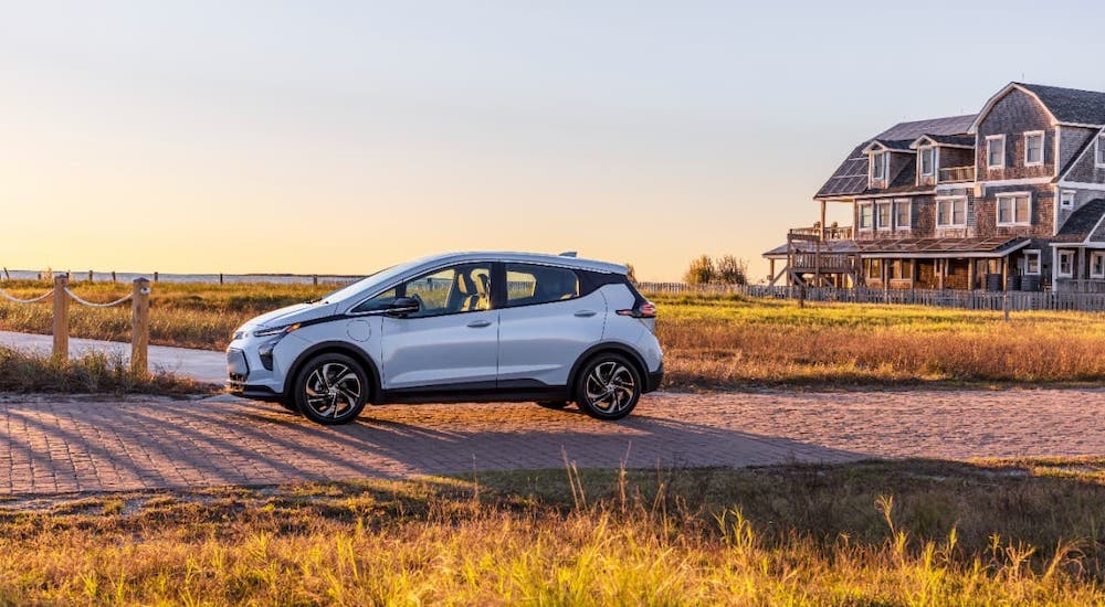 A pale blue 2022 Chevy Bolt EV is shown from the side parked in front of a beach house.