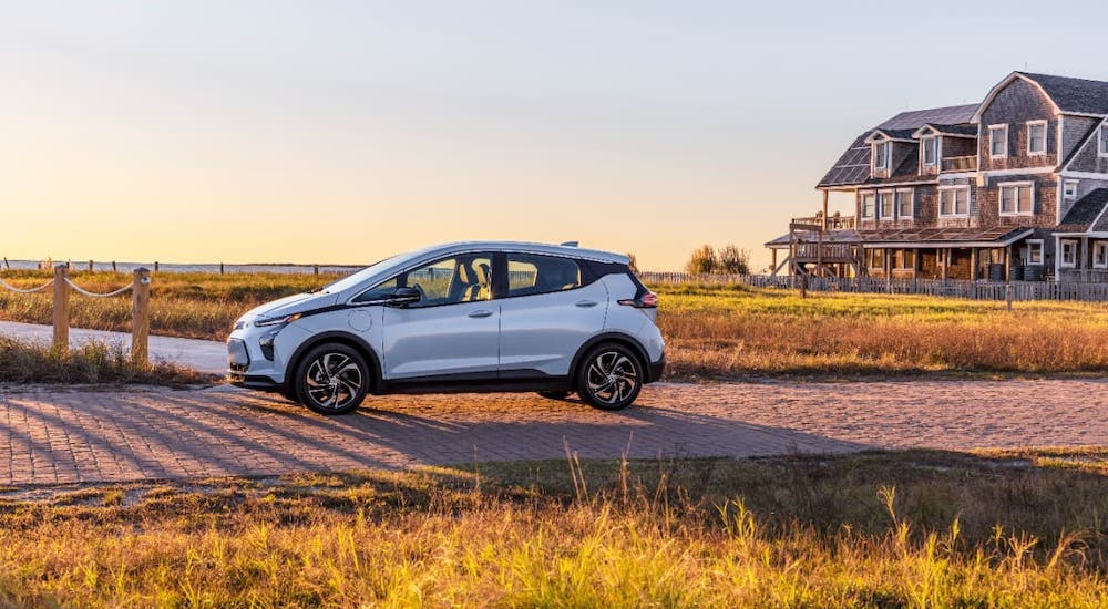 A silver 2022 Chevy Bolt EV is shown from the side parked in front of a beach house.