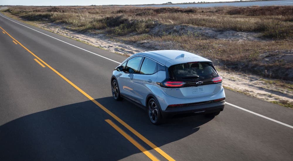 A silver 2022 Chevy Bolt EV is shown from a high angle from behind while driving on an empty highway.